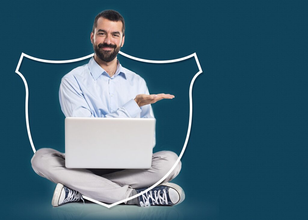 Un homme avec une barbe, assis en tailleur, tient un ordinateur portable ouvert tout en présentant un bouclier blanc dessiné autour de lui. Il sourit et sa main est ouverte en signe de présentation.