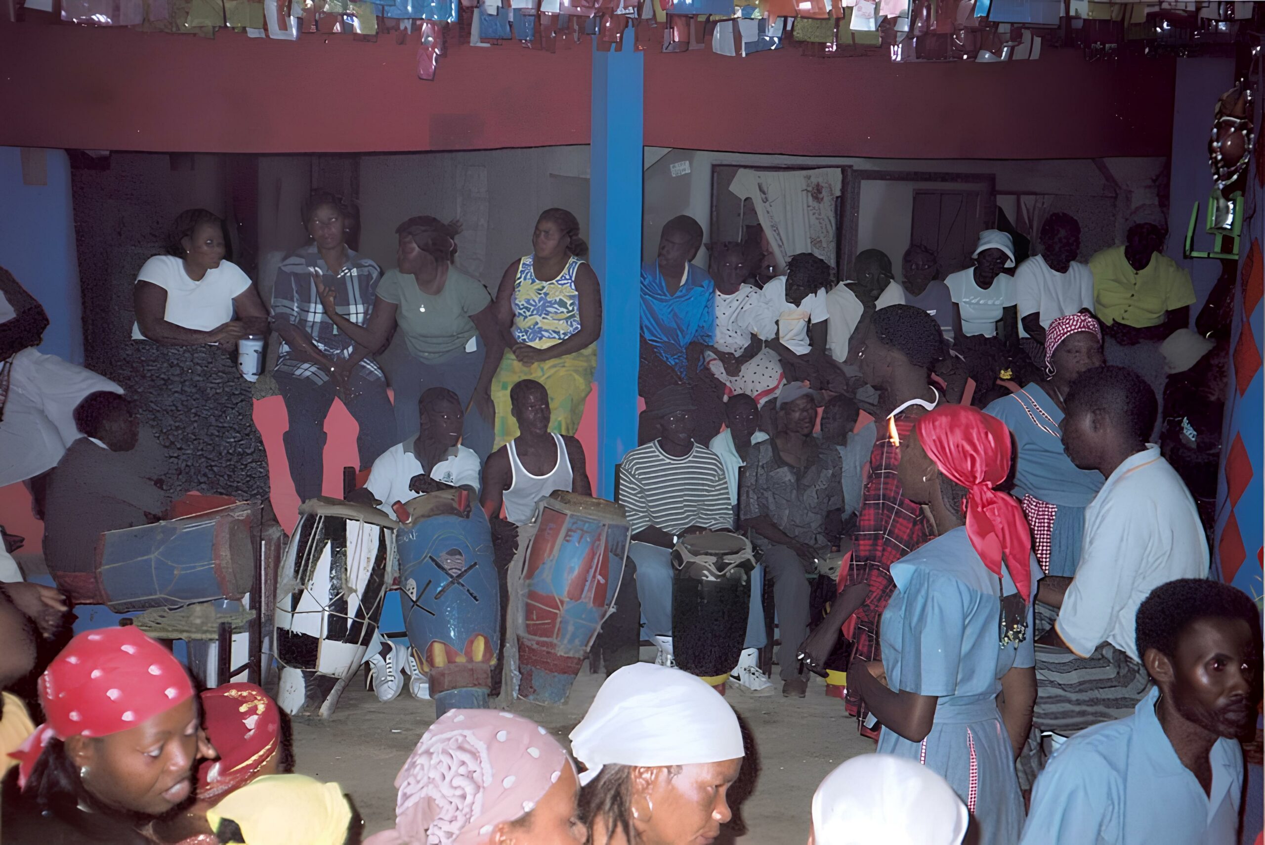 Photographie d'une authentique cérémonie vaudou à Jacmel en Haïti, montrant un initié en train de tracer un vévé au sol avec de la farine au pied du poteau-mitan.